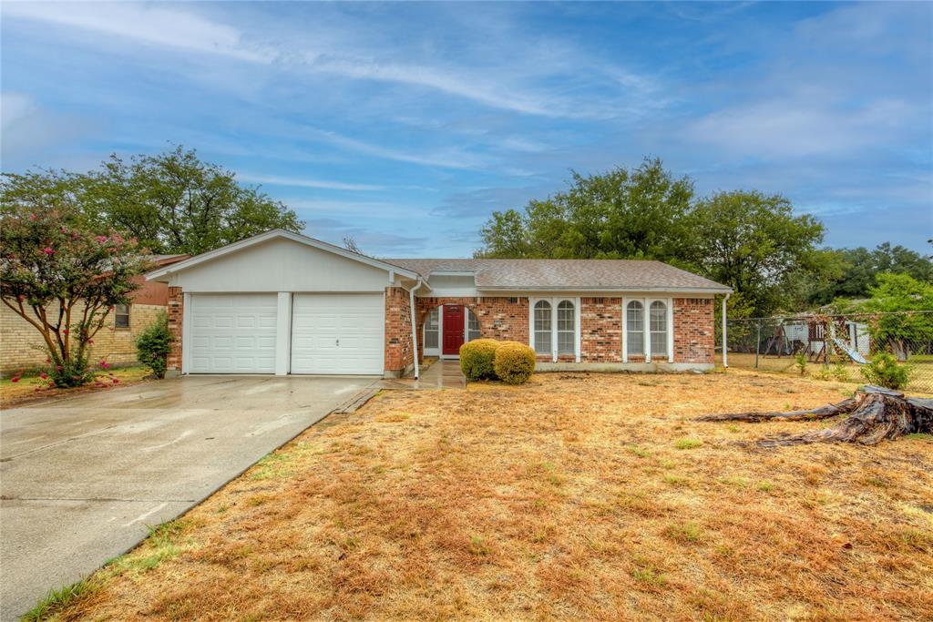 a front view of house with yard and trees in the background