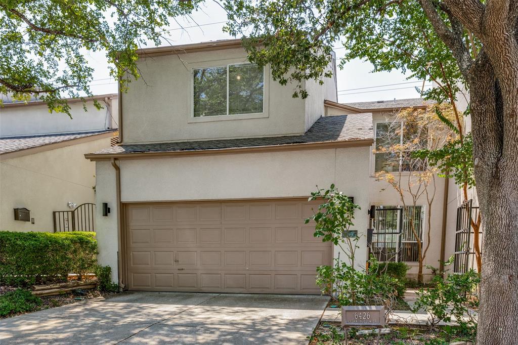 a front view of a house with a yard garage and tree