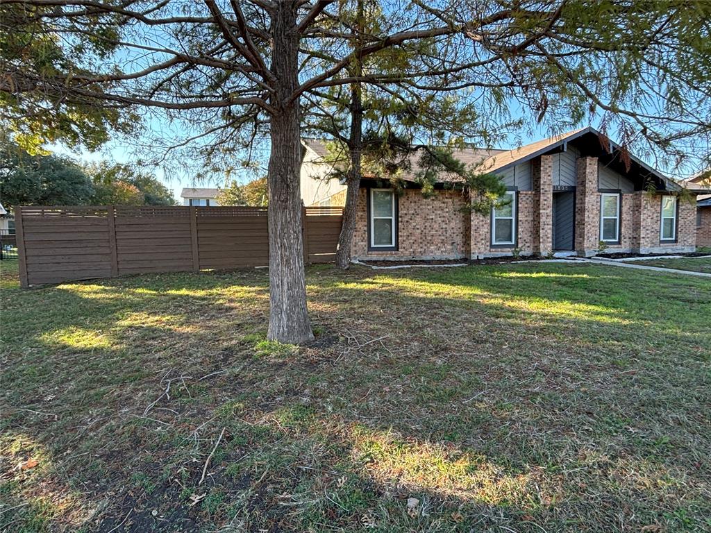 a view of a house with a yard and large tree