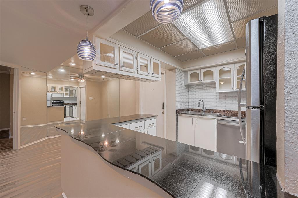 a kitchen with stainless steel appliances granite countertop a sink cabinets and wooden floor