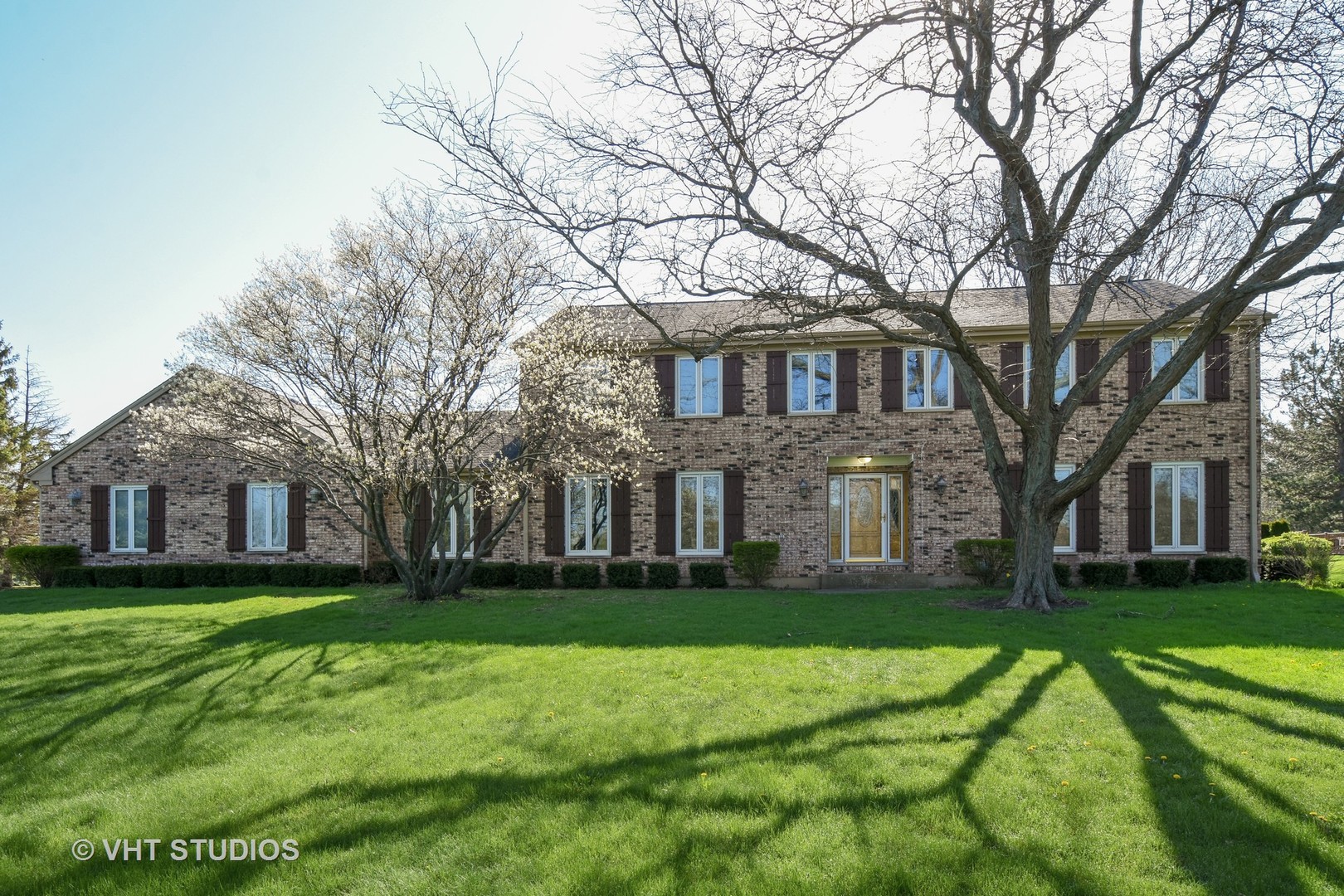 a white house with a big yard and large trees