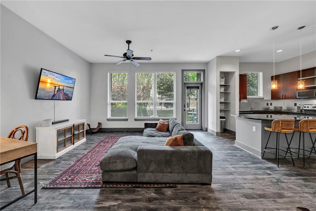 a living room with furniture large window and kitchen view