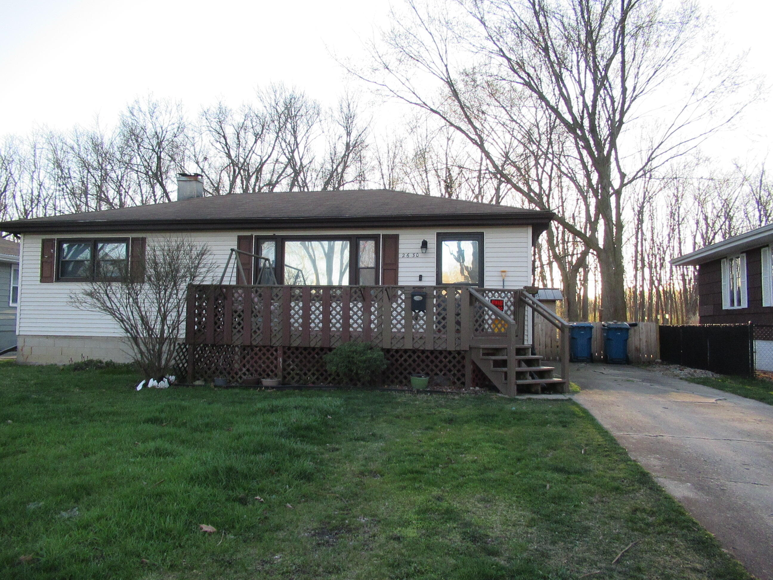 a front view of a house with garden and trees