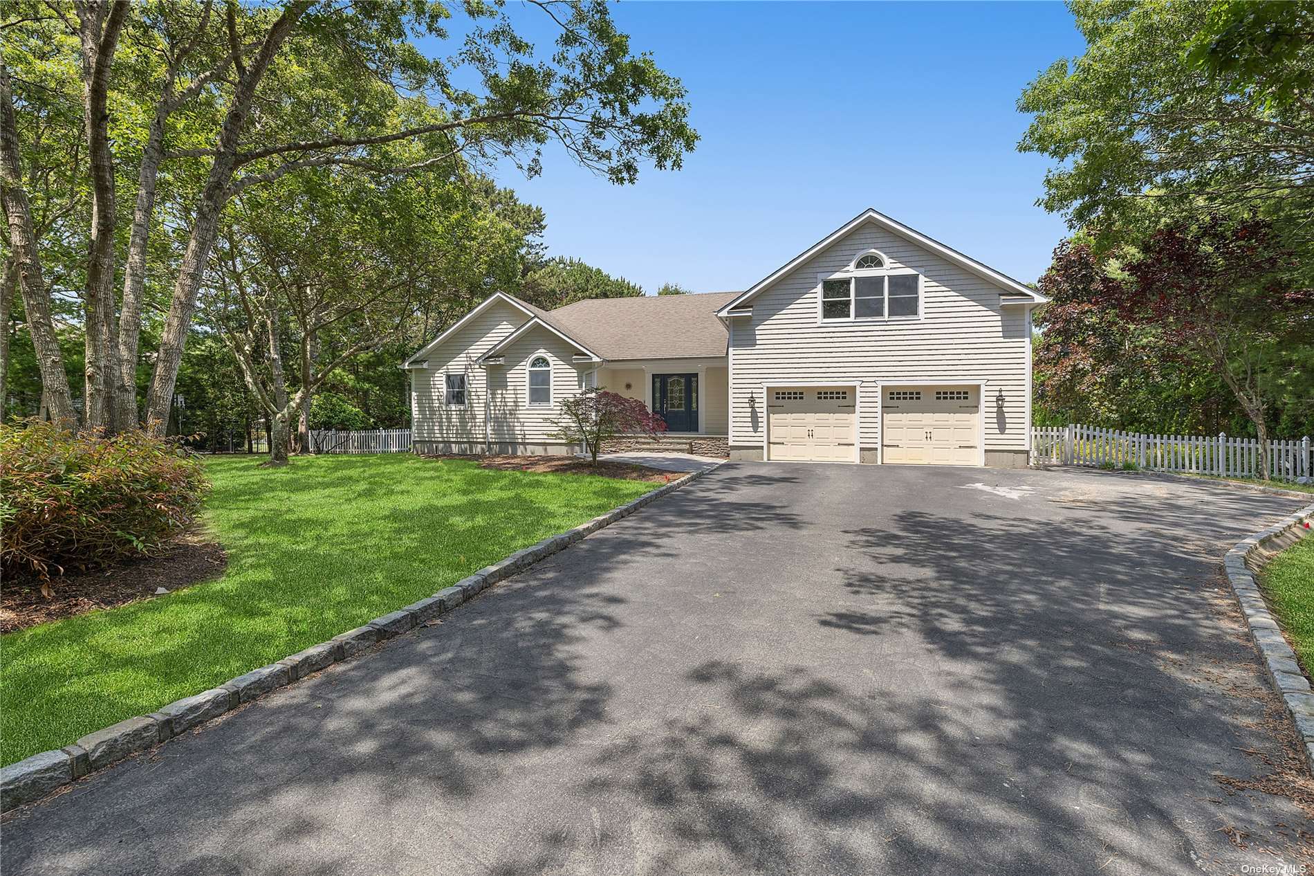 a front view of a house with a yard and large trees