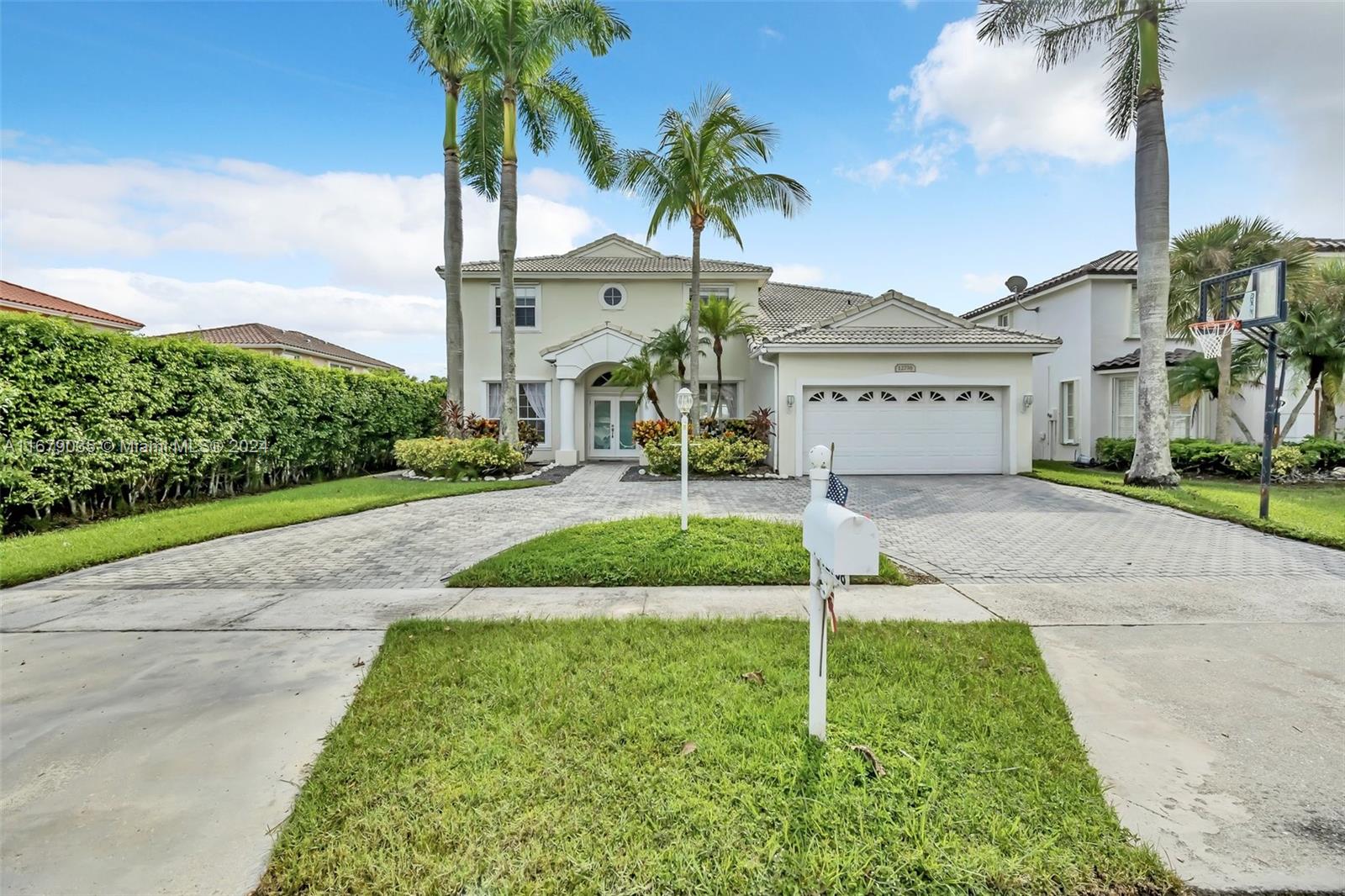 a front view of a house with a yard and palm trees