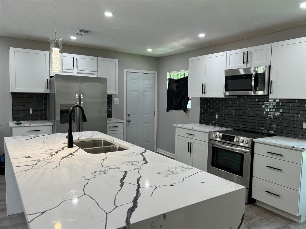 a kitchen with stainless steel appliances kitchen island granite countertop a sink a stove and cabinets