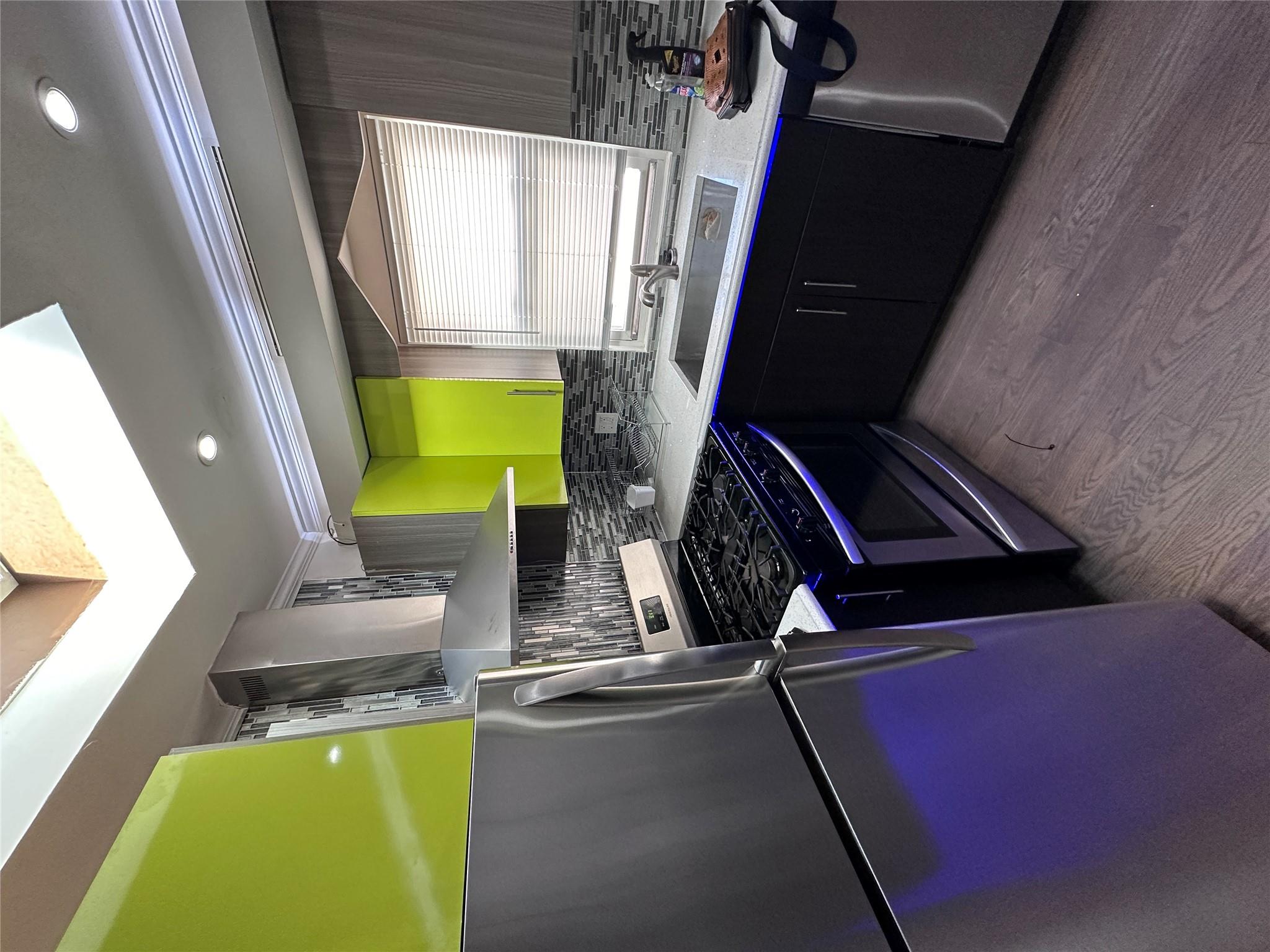 Kitchen with stove, exhaust hood, sink, light hardwood / wood-style floors, and fridge