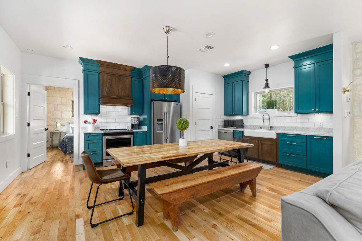 a kitchen with stainless steel appliances kitchen island granite countertop a sink a stove and a wooden floors