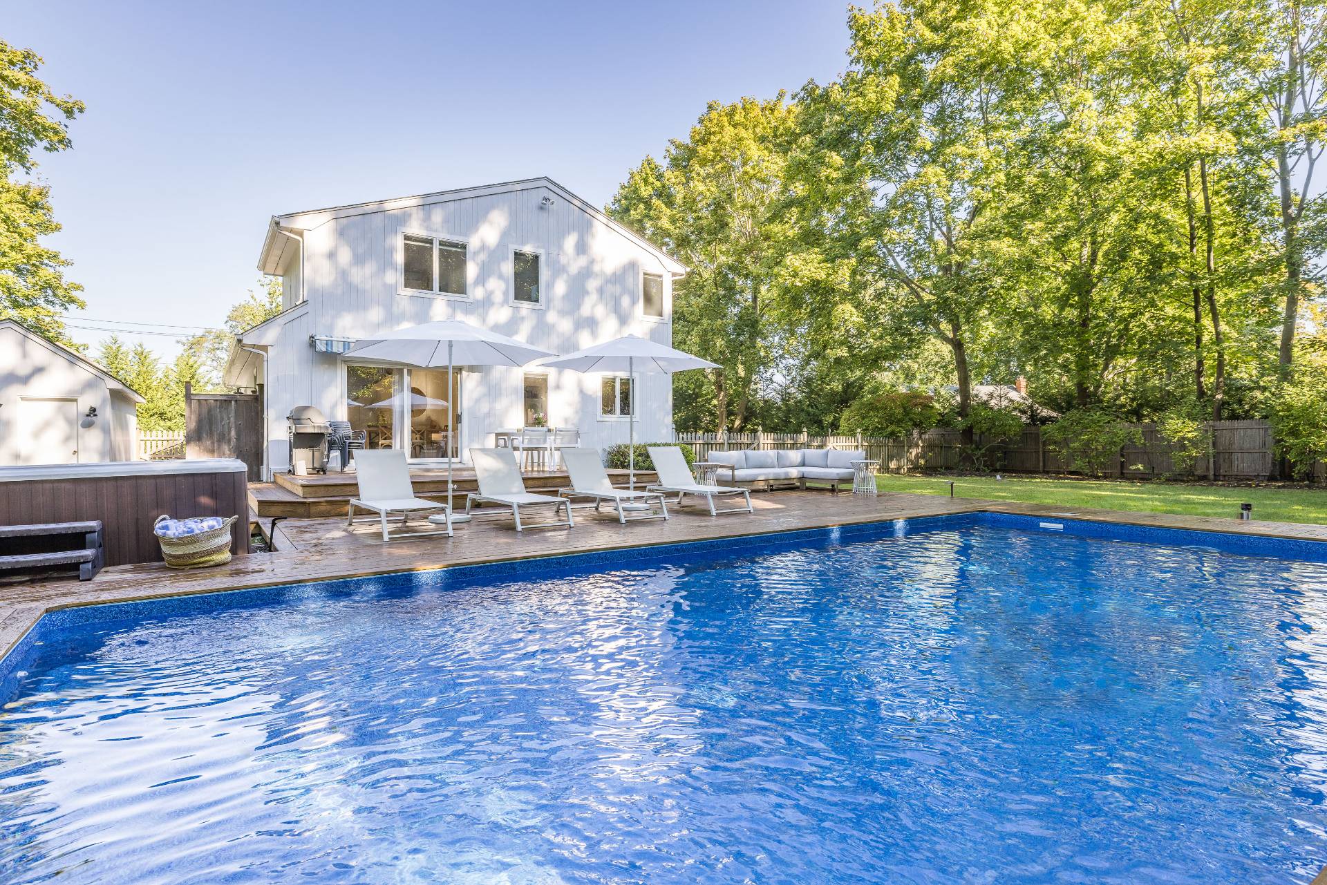 a view of pool with lawn chairs and wooden fence