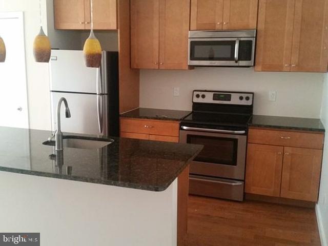 a kitchen with stainless steel appliances granite countertop a refrigerator stove and microwave