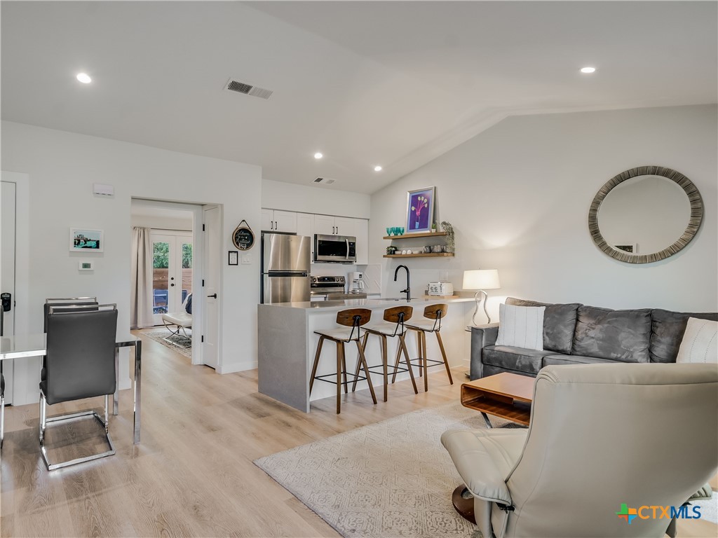 a living room with furniture and a dining table with kitchen appliances