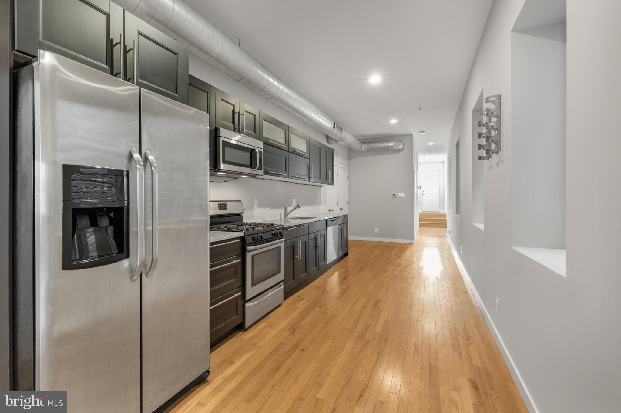 a kitchen with stainless steel appliances a refrigerator and a wooden floor