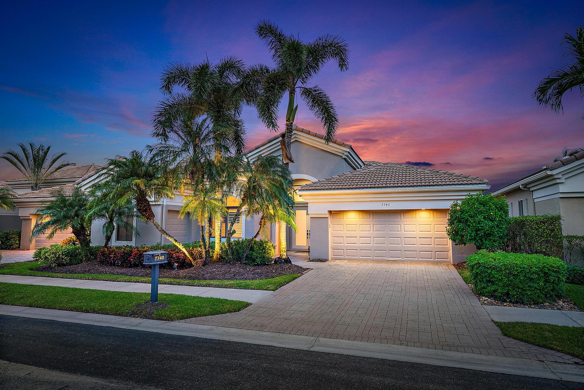 a front view of a house with a yard and palm trees