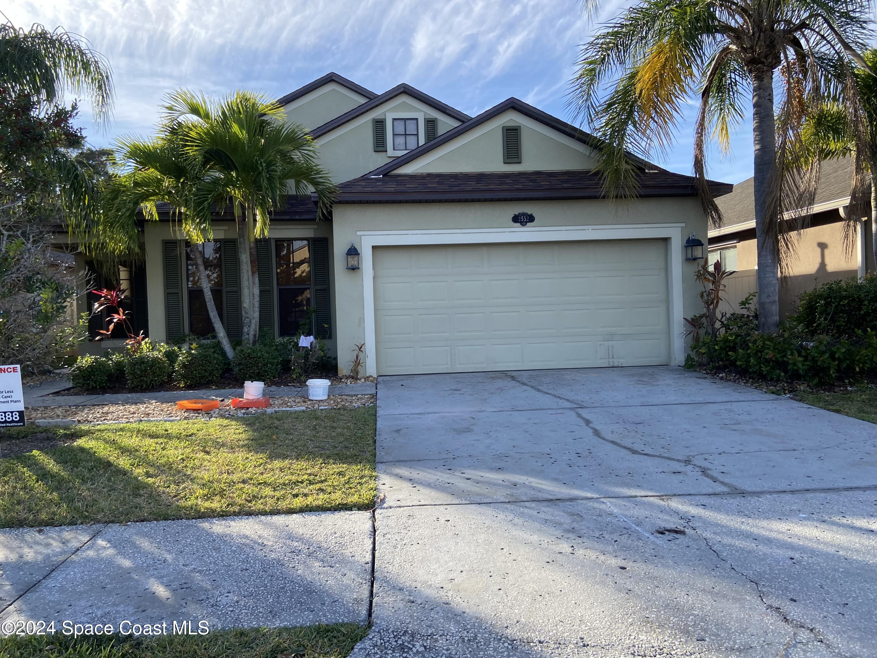 front view of house with a yard and palm trees