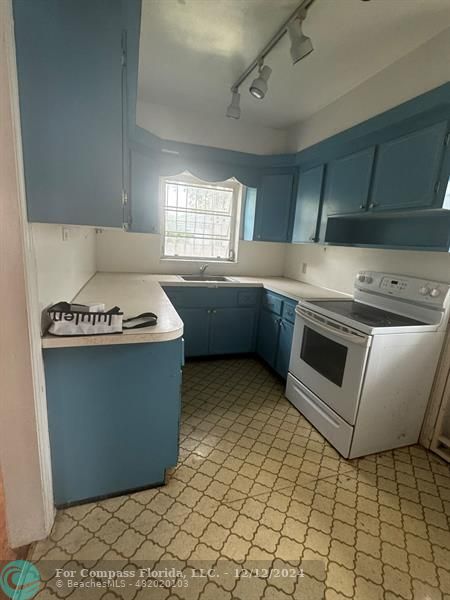 a kitchen with granite countertop a sink a stove and cabinets