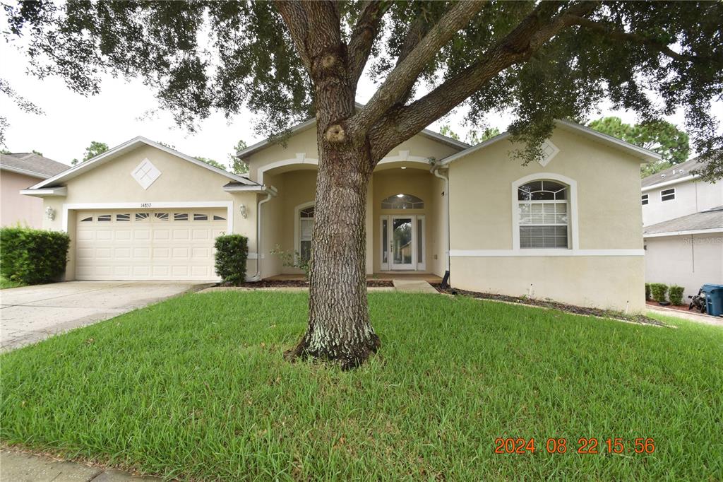 a front view of a house with a yard and trees