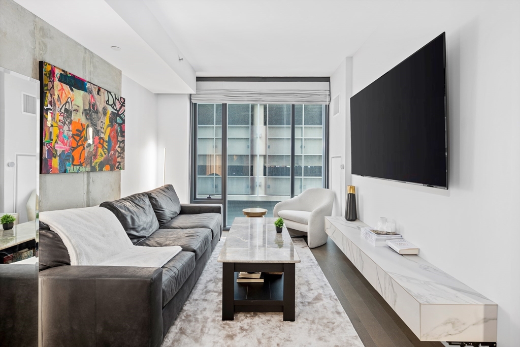 a living room with furniture a flat screen tv and a floor to ceiling window