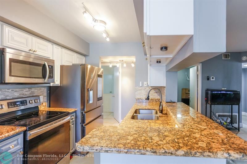 a kitchen with stainless steel appliances granite countertop a sink stove and refrigerator