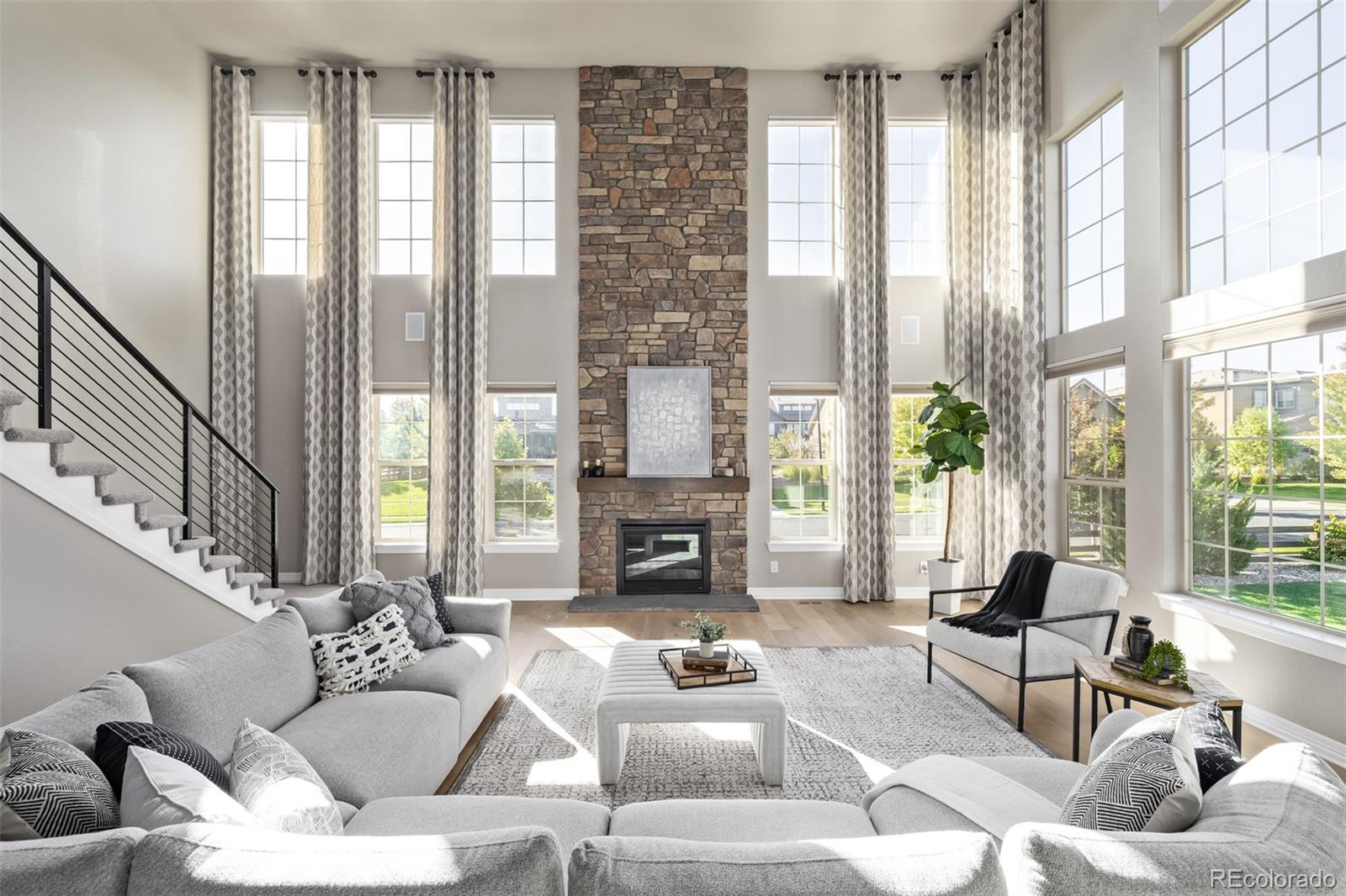 a living room with furniture large windows and wooden floor