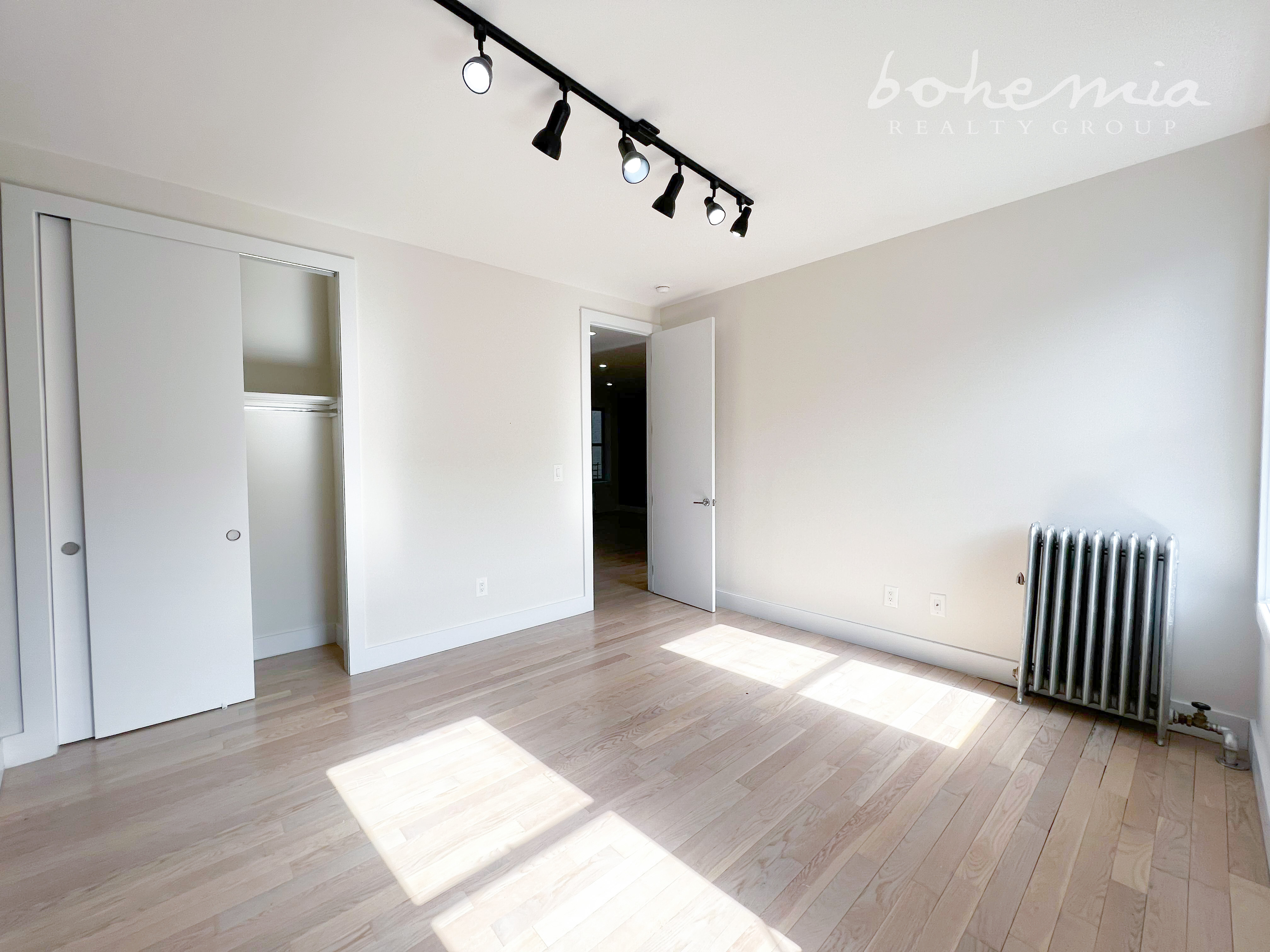 a view of an empty room with wooden floor and stairs