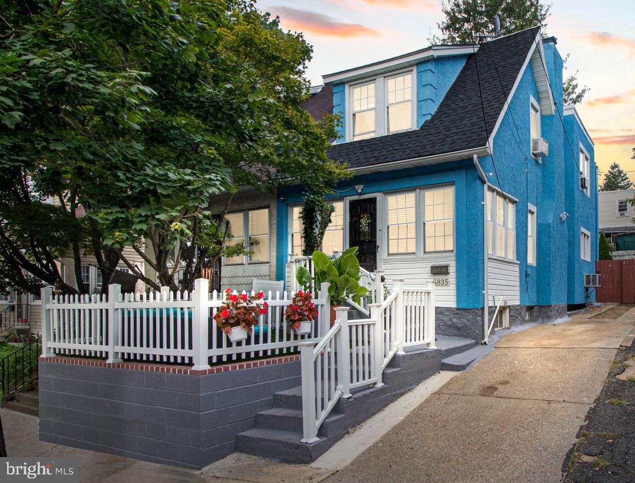 a view of a house with a small yard and a large tree