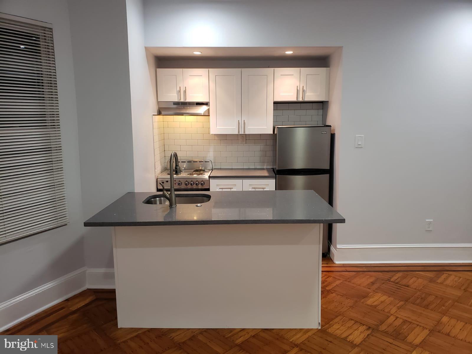 a kitchen with kitchen island a sink a stove and a refrigerator