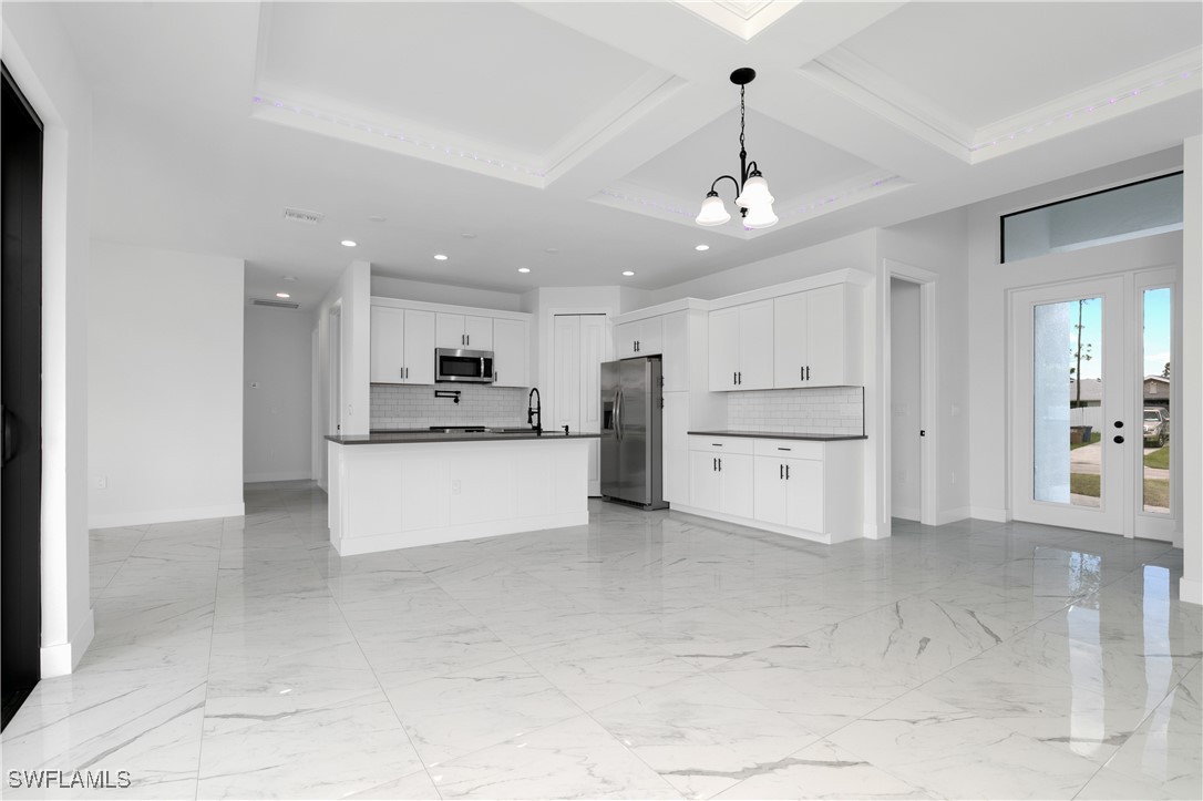 a view of kitchen with kitchen island white cabinets and stainless steel appliances