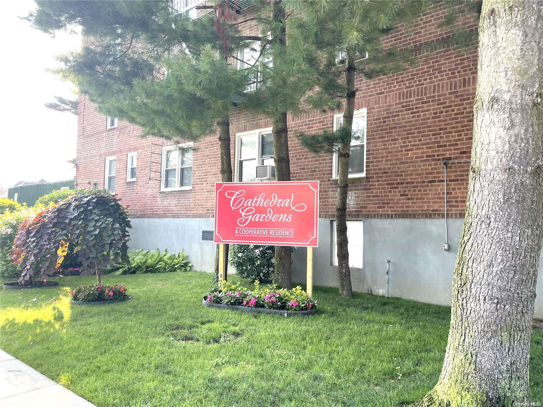 a sign that is sitting in front of a house with a tree