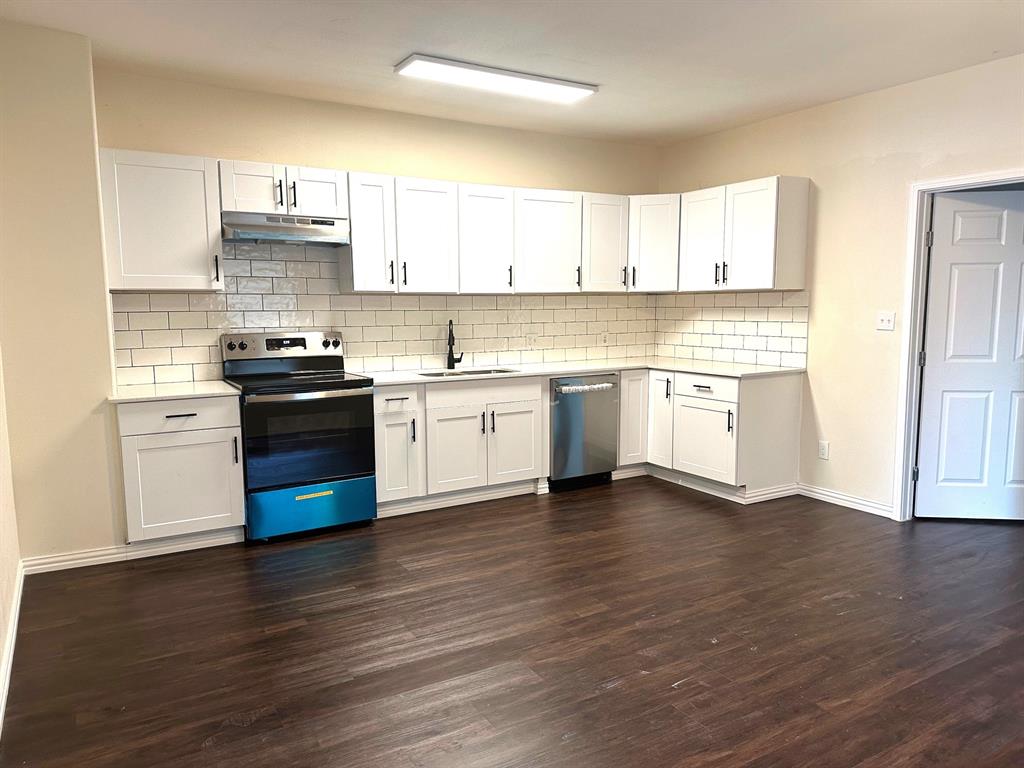 a kitchen with stainless steel appliances granite countertop a stove cabinets and wooden floor