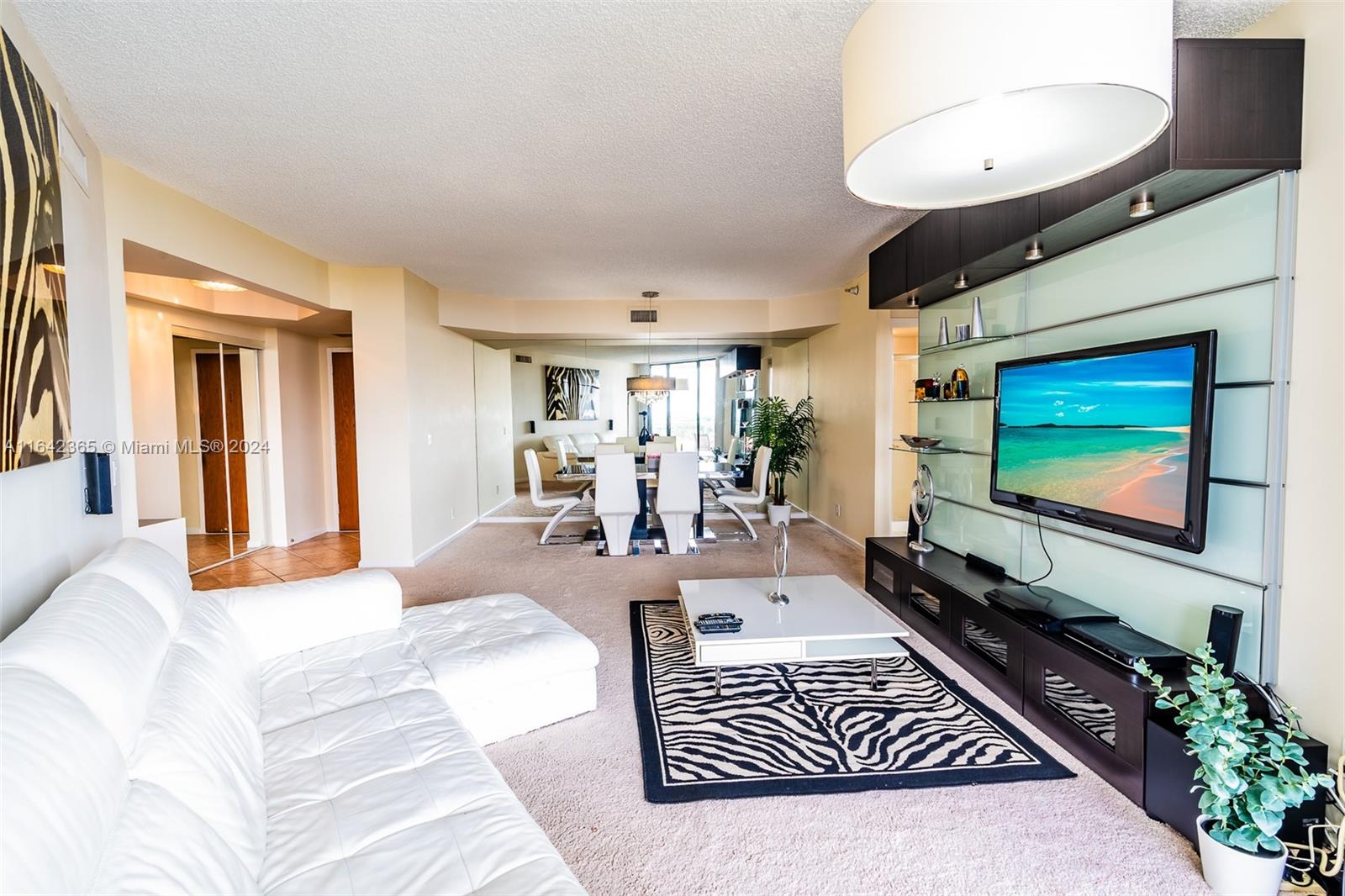 a living room with furniture a flat screen tv and a large window