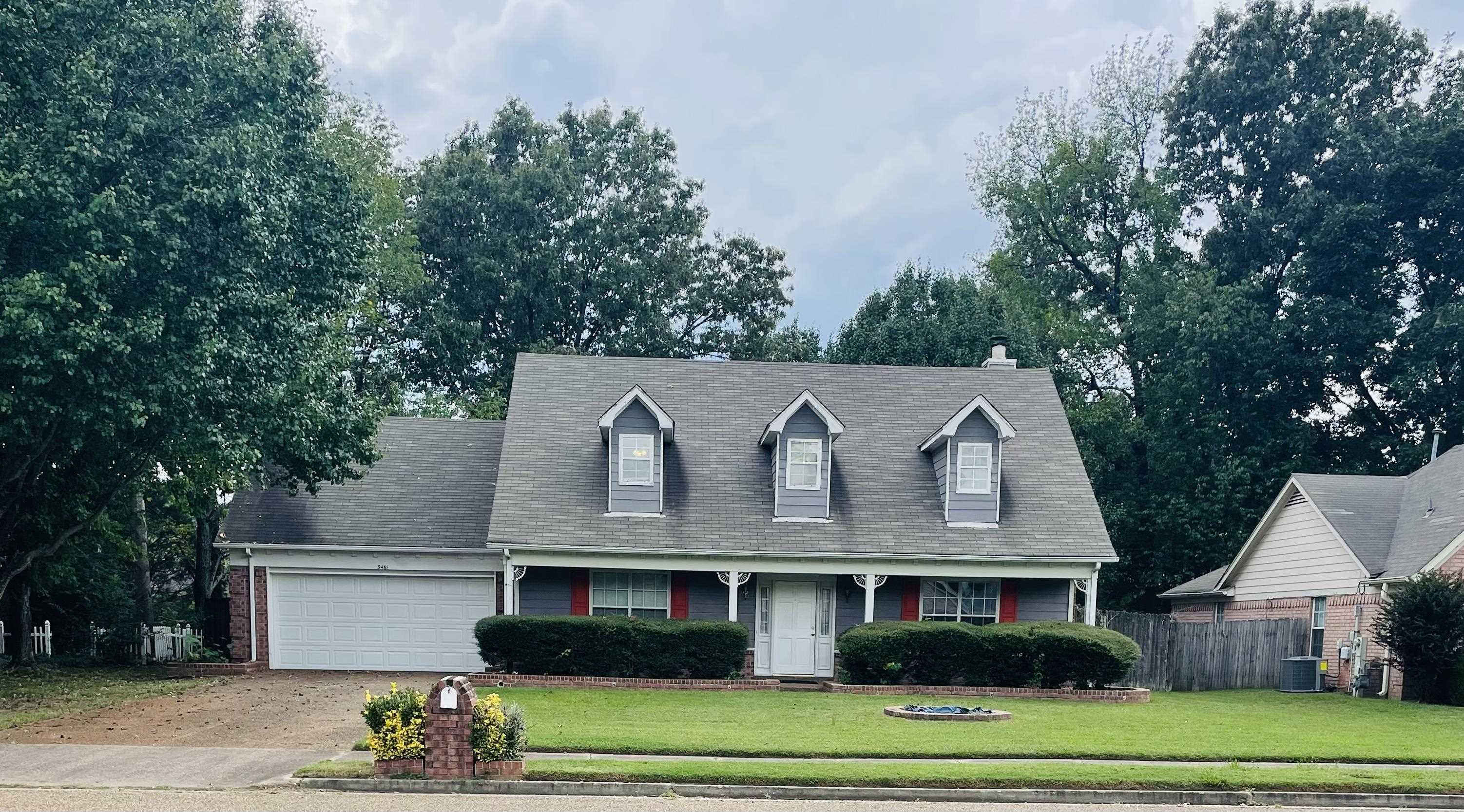 a front view of a house with a garden and trees