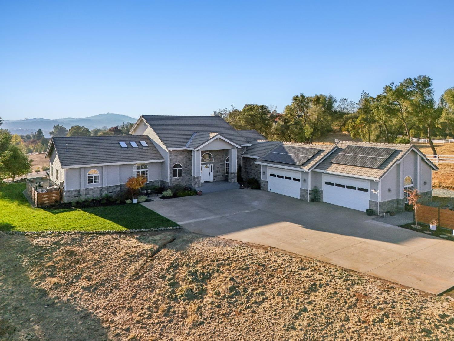 a view of a big house with a big yard plants and large trees