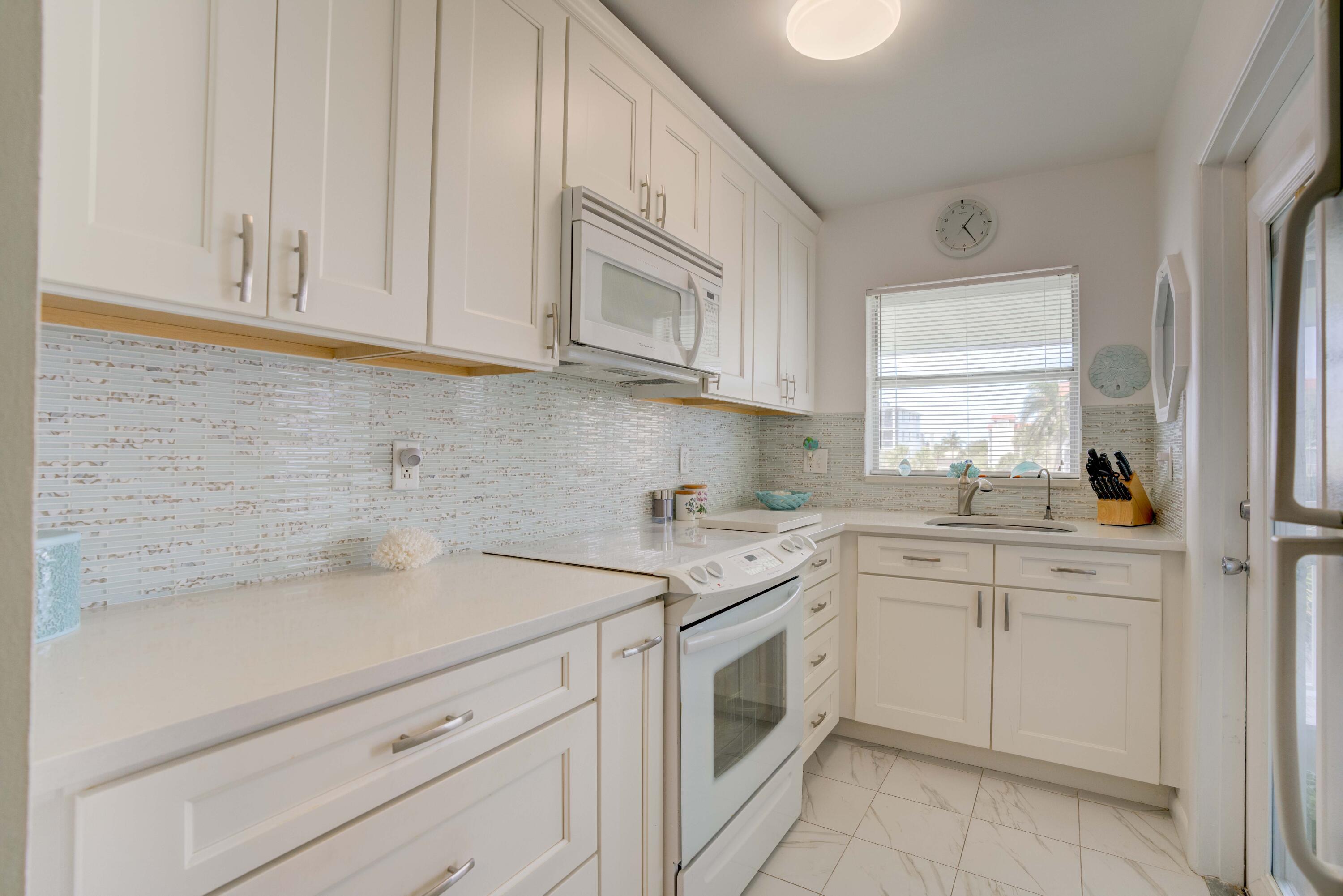 a kitchen with white cabinets appliances a sink and a window