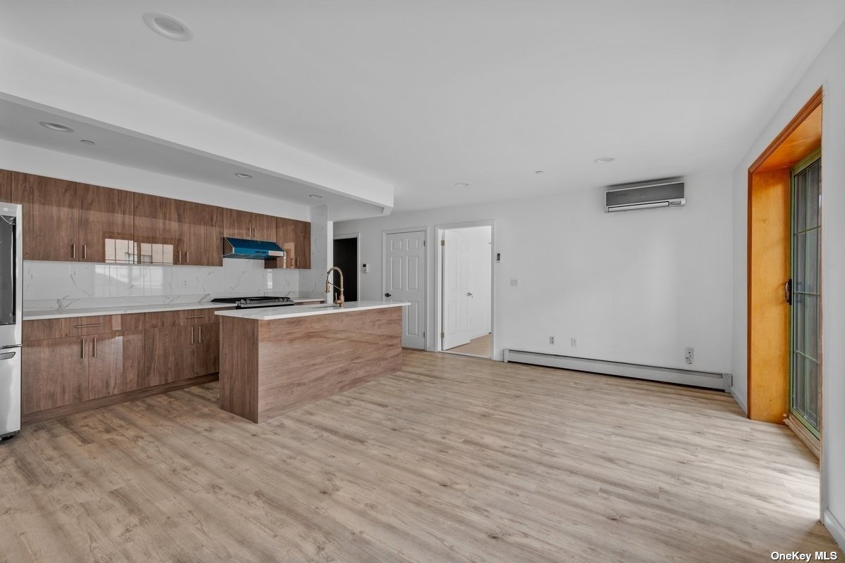 a large kitchen with a wooden floor and stainless steel appliances