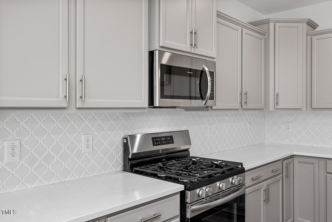 a kitchen with white cabinets and a stove top oven