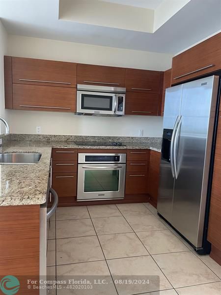 a kitchen with stainless steel appliances granite countertop a refrigerator and a stove