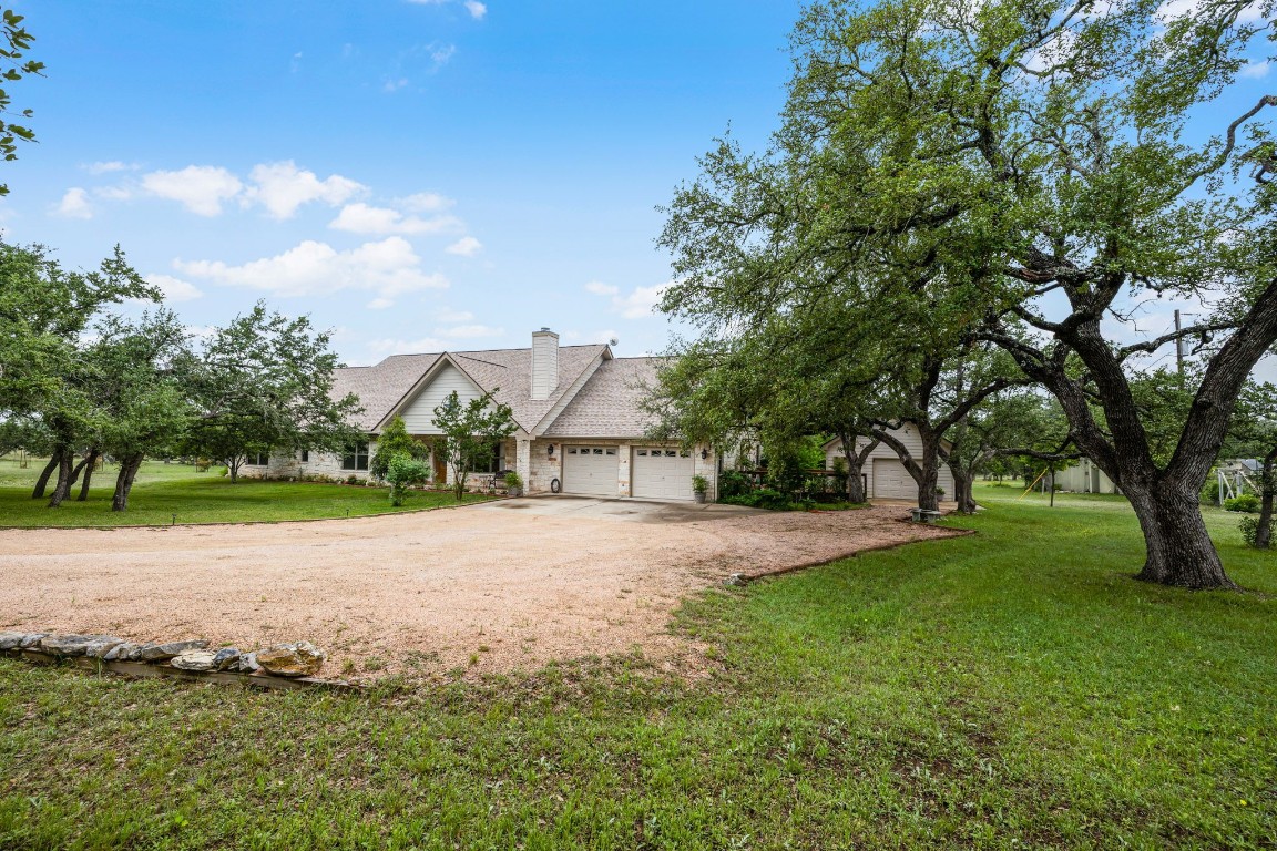 a view of a house with a big yard and large trees