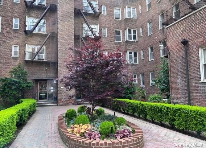 a front view of a multi story residential apartment building with yard and green space