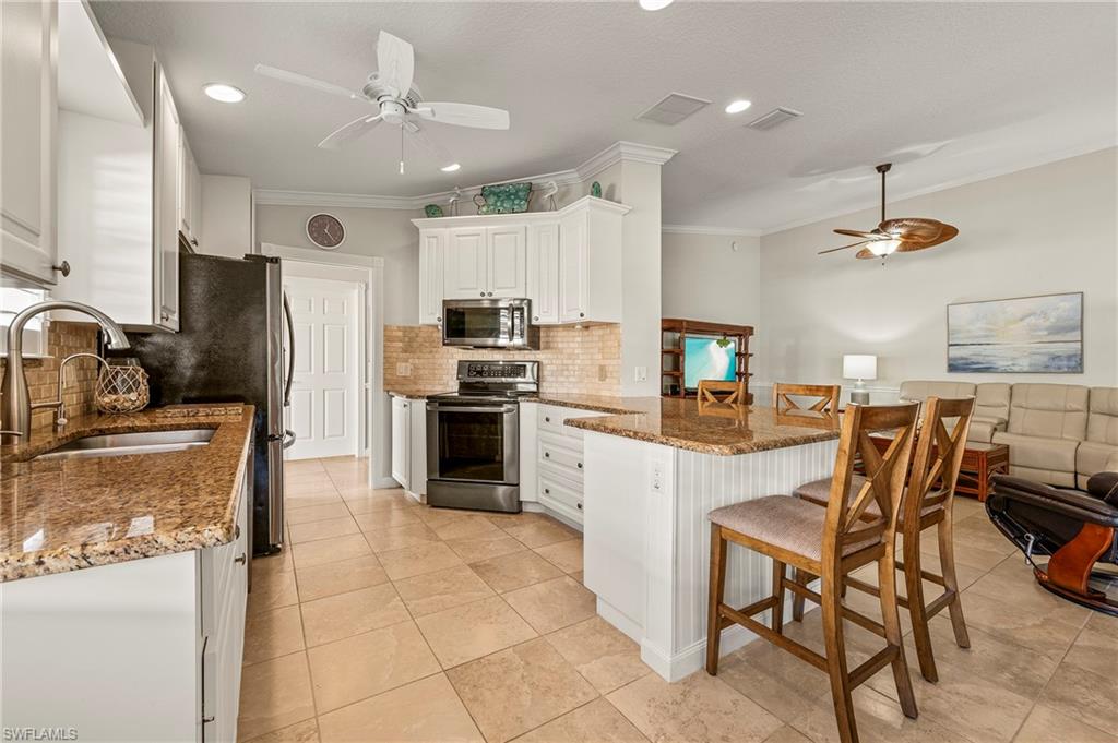 a kitchen with kitchen island granite countertop a sink appliances cabinets and furniture