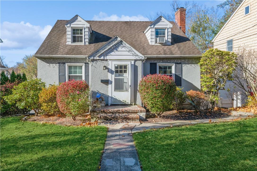 Cape cod house featuring a front yard