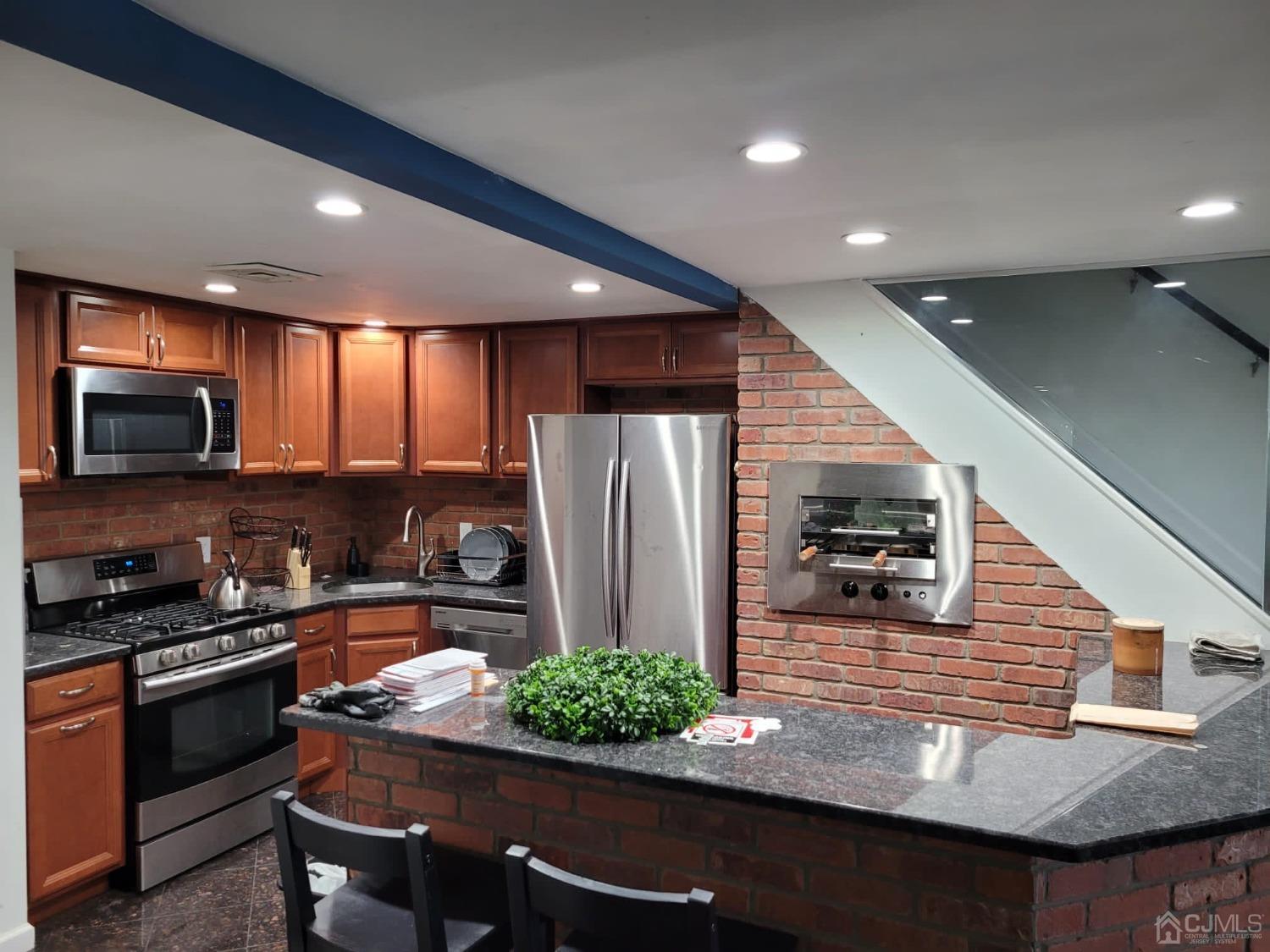 a kitchen with stainless steel appliances granite countertop a refrigerator and a stove top oven