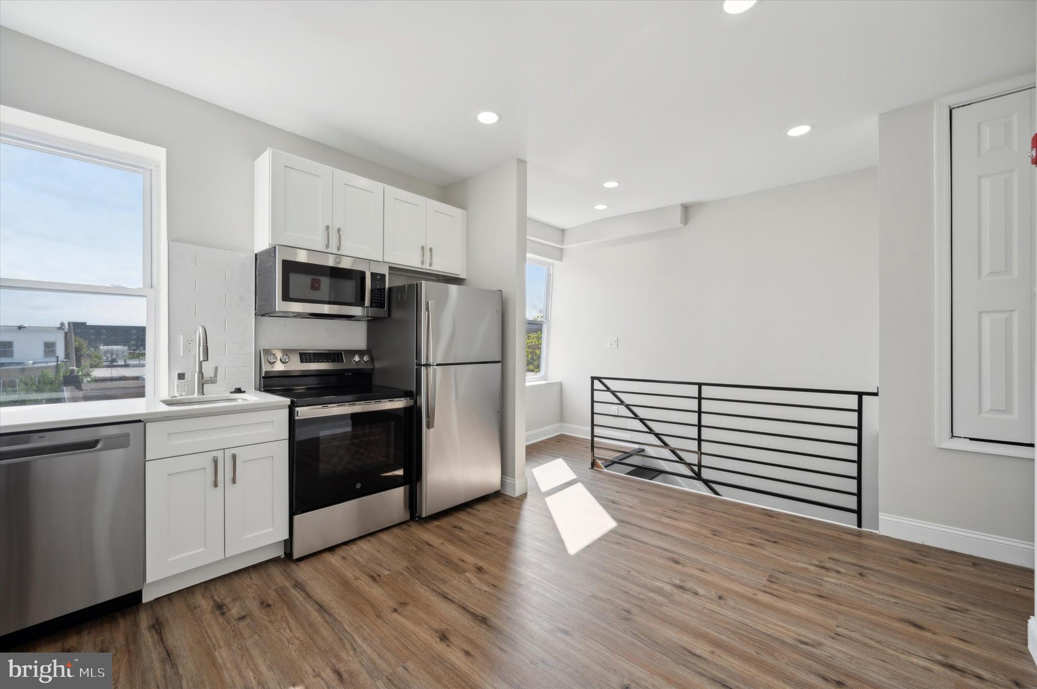 a kitchen with wooden floors and stainless steel appliances