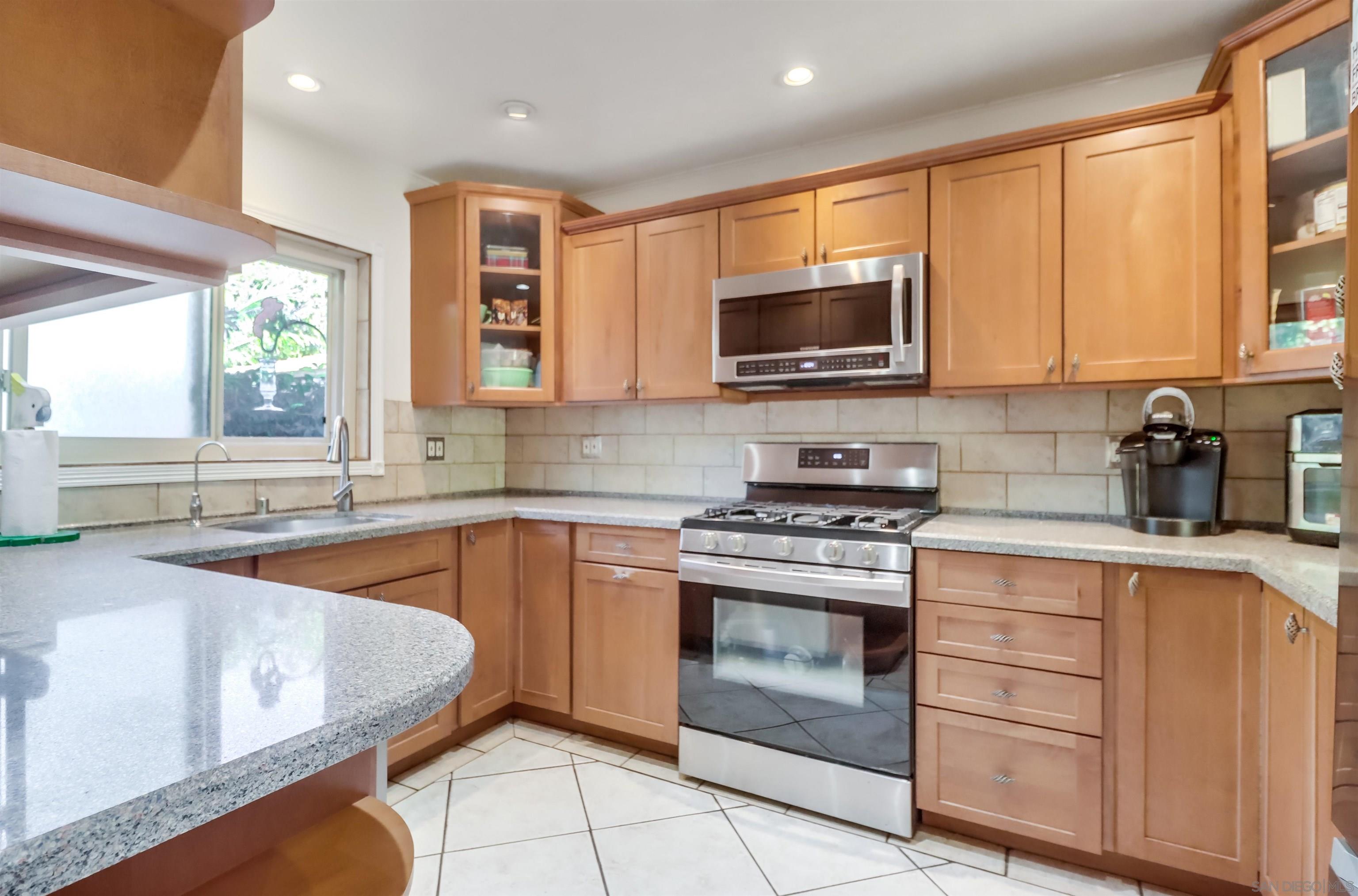 a kitchen with stainless steel appliances granite countertop a stove a sink and a microwave