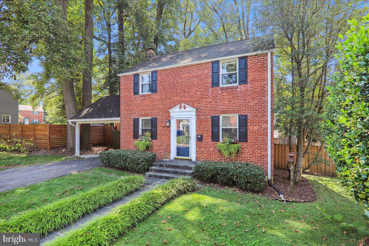 a view of a brick house with a yard and large trees