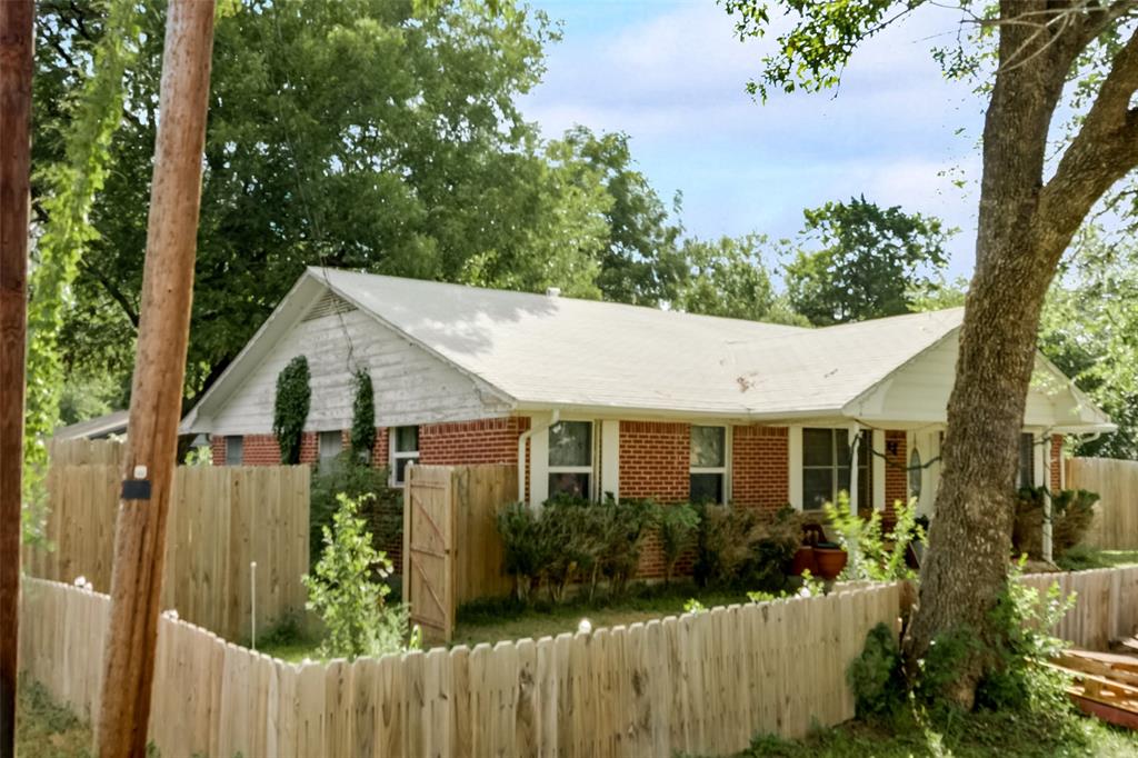 a view of a house with wooden fence next to a yard