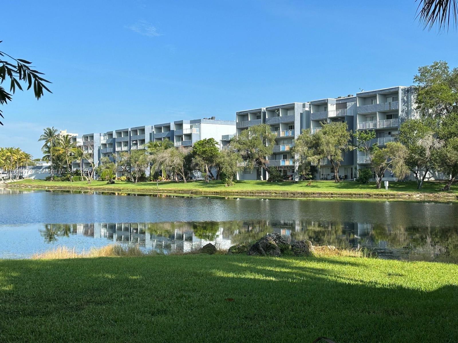 a view of a lake with a big yard and large trees