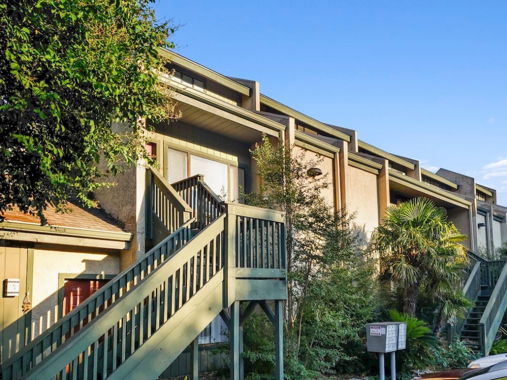 a front view of a house with balcony and trees