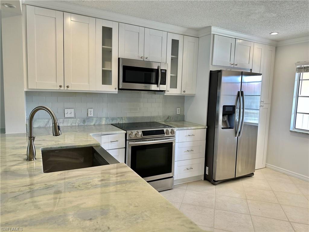 a kitchen with stainless steel appliances granite countertop a refrigerator sink and stove