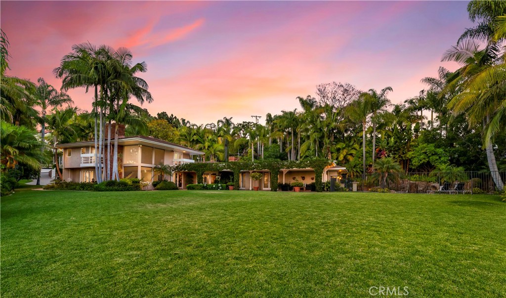 a view of a house with a big yard and large trees