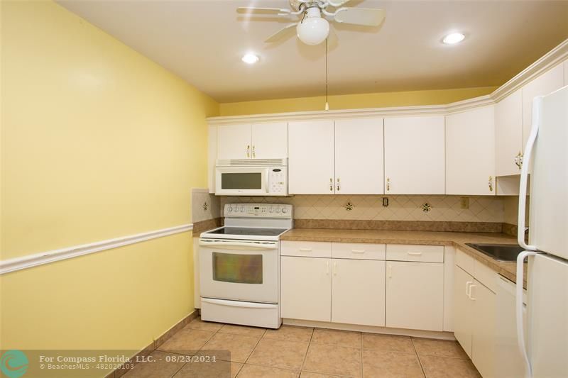 a kitchen with a sink a stove and white cabinets